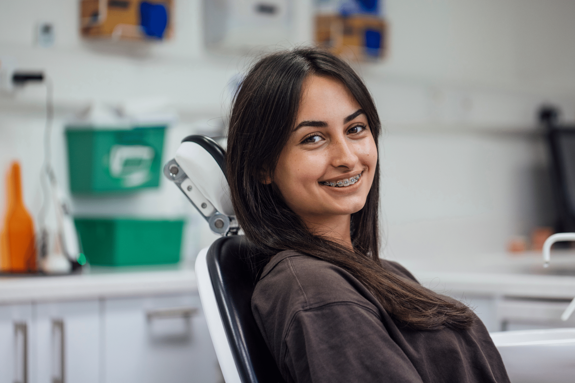 Smiling young woman wearing metal braces in an orthodontic treatment chair